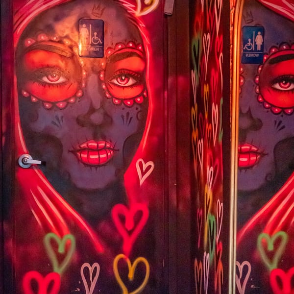 Restroom doors painted with Day of the Dead-style faces and colorful hearts.