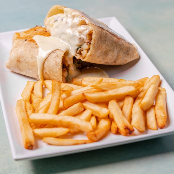Two grilled burritos topped with creamy sauce, served with golden French fries on a white plate.